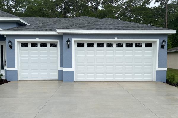 New construction home with classic raised short panel garage doors and plain glass windows.